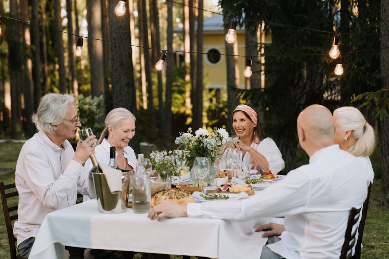 Mastering the First Impression: Your intriguing post title goes here Senior group enjoying a delightful outdoor dinner party with laughter and wine.